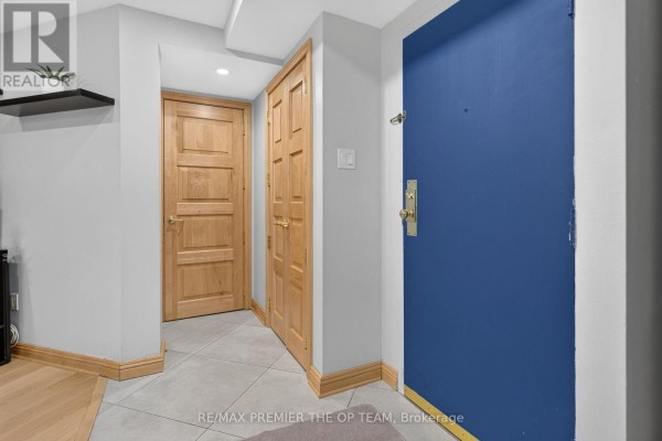 Interior hallway with light gray walls, tiled floor, and wooden doors. - 404 - 100 Arbors Lane, Vaughan