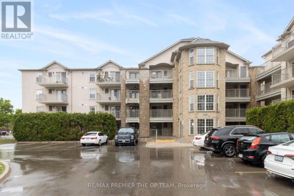 Front view of the building featuring stone accents and parking spaces - 404 - 1440 Bishops Gate, Oakville