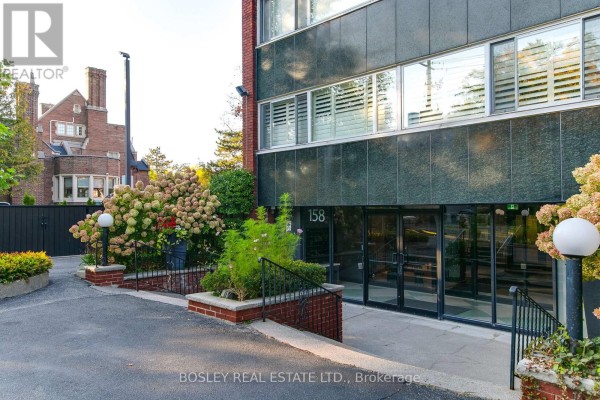 Entrance to the apartment building at 158 Crescent Road with glass doors and brick planters. - 404 - 158 Crescent Road, Toronto