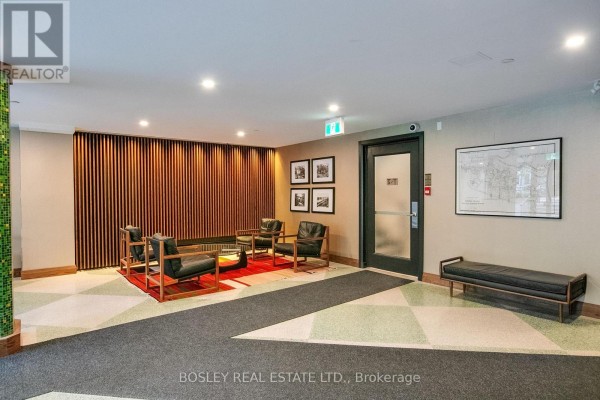 Apartment building lobby with a seating area, patterned carpet, wood paneled wall, and artwork. - 404 - 158 Crescent Road, Toronto