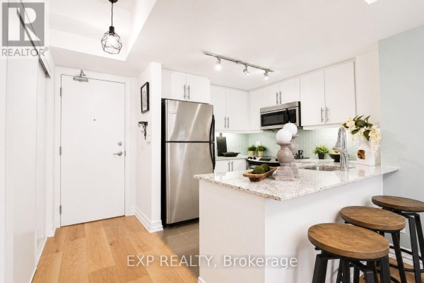Bedroom with king-size bed, ornate chandelier, artwork, and balcony access. - 404 - 500 St Clair Avenue W, Toronto