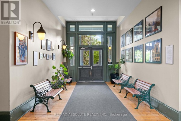 Apartment hallway with dark doors, one labeled 404, and exposed brick archway. - 404 - 589 Rideau Street, Ottawa