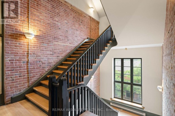 Interior hallway with a modern staircase, metal railings, wooden floors, and mirrored doors. - 404 - 589 Rideau Street, Ottawa