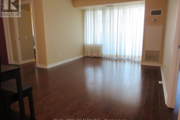 Living area with dark wood floors, beige walls, and large white floor-to-ceiling curtains. - 404 - 61 Town Centre Court, Toronto