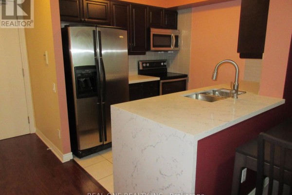 Kitchen counter with sink and faucet, dark cabinets, and stainless steel refrigerator. - 404 - 61 Town Centre Court, Toronto