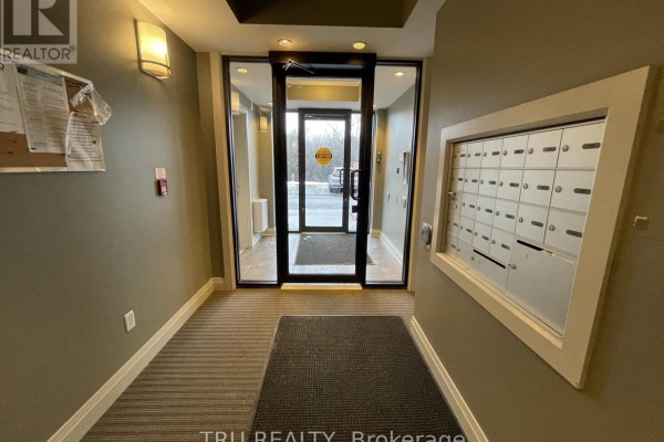 Apartment building lobby with gray walls, a grey patterned carpet, a mailbox bank, and glass doors. - 404 - 655 Beauparc Private, Ottawa