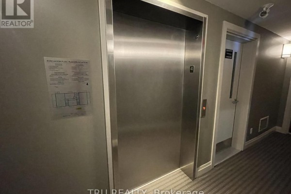 Interior hallway with a brushed stainless steel elevator door, adjacent to a fire escape plan and another door. - 404 - 655 Beauparc Private, Ottawa