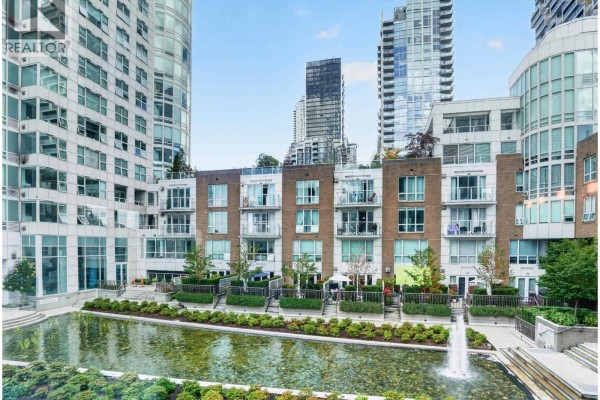 Exterior view of a tall apartment building with a marina and other buildings nearby. - 404 1501 Howe Street, Vancouver