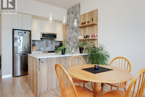 Kitchen with stainless steel appliances, island, and wood-accented cabinetry. - 404 1588 North Dairy Rd, Saanich