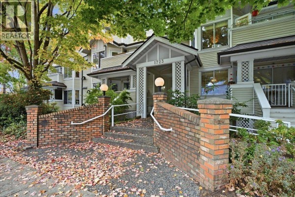 Apartment building exterior with beige siding, white trim, and green trees. - 404 1723 Frances Street, Vancouver