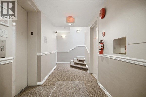 Interior building hallway with elevators, stairs, and exit sign. - 404 1723 Frances Street, Vancouver