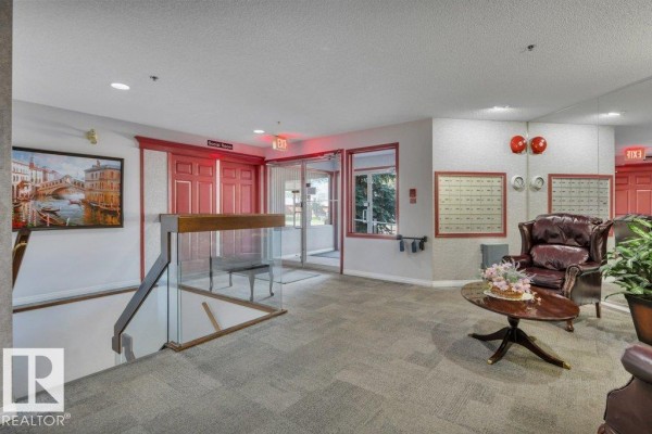 Apartment building lobby with carpet, red doors, mailboxes, and leather armchairs. - #404e 17511 98a Av Nw, Edmonton