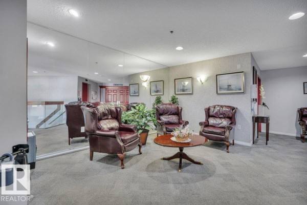 Lobby area with a large mirror reflecting leather armchairs, plants, and wall sconces. - #404e 17511 98a Av Nw, Edmonton