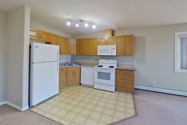 Kitchen with wood cabinets, white appliances, and beige tiled flooring. - #404 9945 167 St Nw, Edmonton