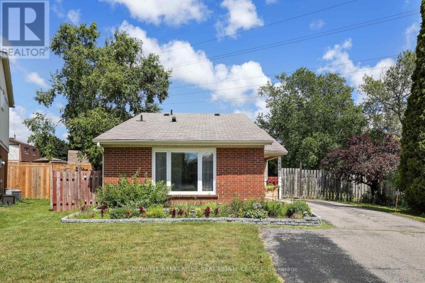 Driveway and entryway of a red brick bungalow with a decorative wreath on the door. - 404 Burnley Court, Oshawa