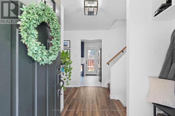 Interior view of a home entrance with a dark grey front door, wreath, and hallway. - 404 Burnley Court, Oshawa