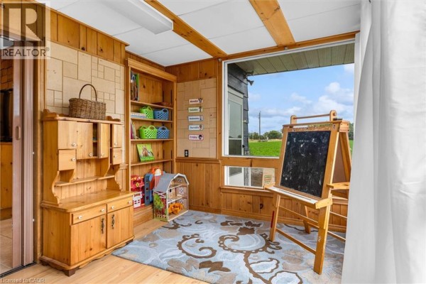 Room with wood paneled walls, built-in hutch, bookshelves, easel, and wood floor. - 404 Concession 5 Road, Fisherville