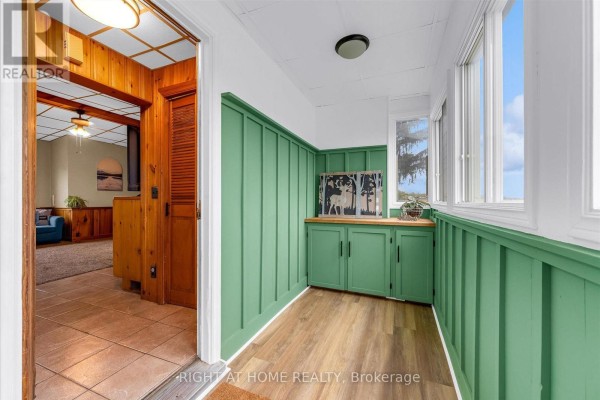Green paneled sunroom with built-in cabinets, wooden trim, and large windows overlooking the exterior. - 404 Concession 5 Road, Haldimand
