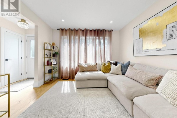 Living room with a sectional sofa, textured rug, artwork, and entrance hallway. - 404 Glen Park Avenue, Toronto