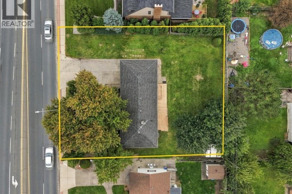 Aerial view of rectangular lot with single-story house, garage, and surrounding trees and yards. - 4045 Dougall Avenue, Windsor