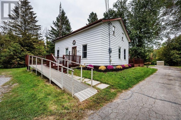 White house with a ramp and deck surrounded by trees. - 4045 Highway 2, Clarington