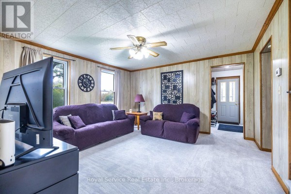 Living room with two purple sofas, a TV, and light wood paneling. - 4045 Highway 2, Clarington