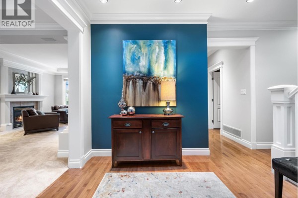 Entryway hallway with blue accent wall, dark wood cabinet, and abstract art. - 4047 Woodbury Avenue, North Vancouver