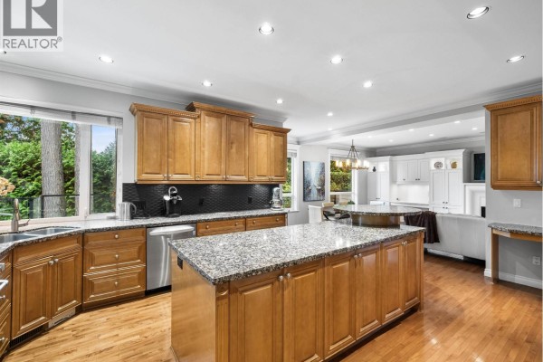 Open-concept kitchen with wood cabinets, granite countertops, and an island. - 4047 Woodbury Avenue, North Vancouver