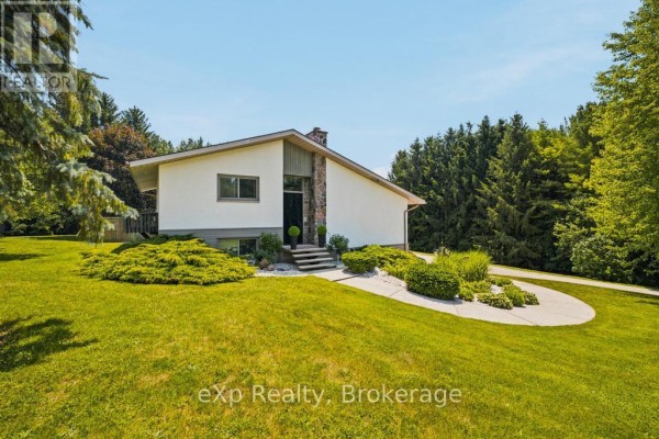 Front exterior of a house with white stucco and stone accents, surrounded by greenery. - 40481 Howick-turnberry Road, Morris Turnberry