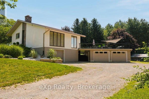 Side exterior view of a house with a three-car garage, deck, and gravel driveway. - 40481 Howick-turnberry Road, Morris Turnberry