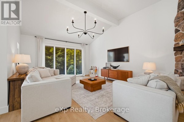 Living room with white sofas, coffee table, entertainment unit, and vaulted ceiling. - 40481 Howick-turnberry Road, Morris Turnberry