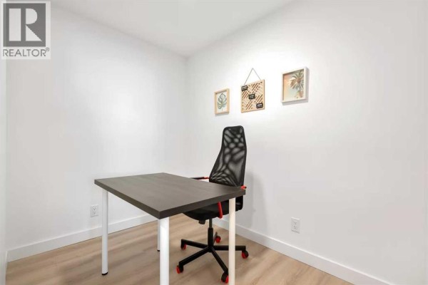 A black Keurig coffee maker sits on a white kitchen counter between two white canisters. - 405, 123 4 Street Ne, Calgary