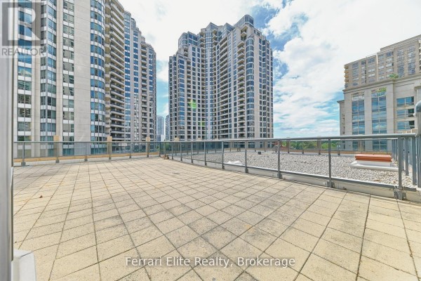 Expansive paved balcony with glass railings and gravel edges, surrounded by apartment buildings. - 405 - 10 Northtown Way, Toronto