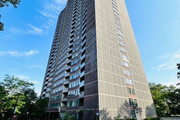 Low angle view of a tall, modern apartment building with a textured grey facade and balconies. - 405 - 3100 Kirwin Avenue, Mississauga