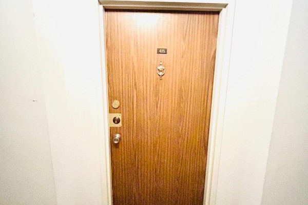 Close-up of a closed wooden apartment door with brass hardware and a knocker, labeled with number 405. - 405 - 3100 Kirwin Avenue, Mississauga