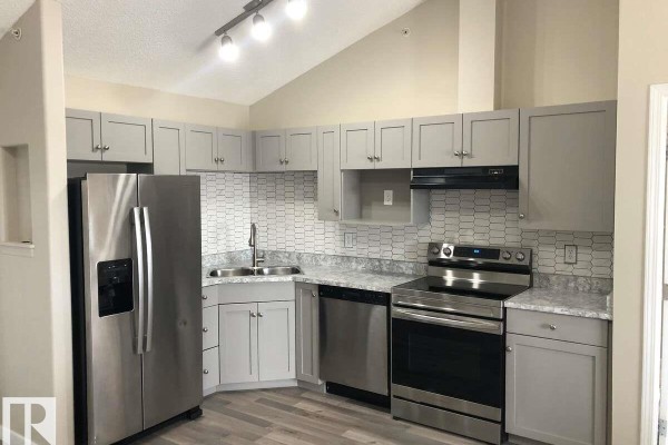 Stacked white front-load washer and dryer in a neutral-colored closet. - #405 151 Edwards Dr Sw, Edmonton