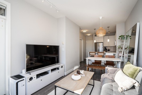 Bedroom with a white bed, grey headboard, and a window overlooking trees. - 405 15388 105 Avenue, Surrey