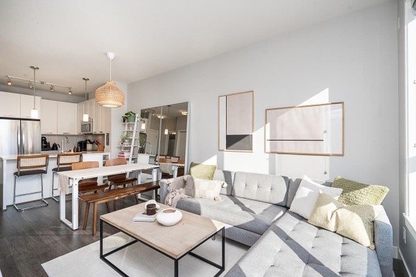 Open concept living, dining, and kitchen area with white furniture and stainless steel appliances. - 405 15388 105 Avenue, Surrey
