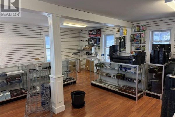 Retail space with wood flooring, glass display cases, and shelves stocked with items. - 405 Victoria Street, Edmundston