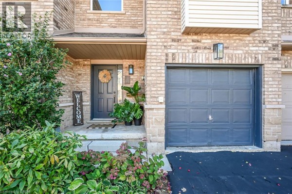 Close-up of the townhouse entrance with a dark gray door, plants, and garage. - 4055 Forest Run Avenue Unit# 89, Burlington