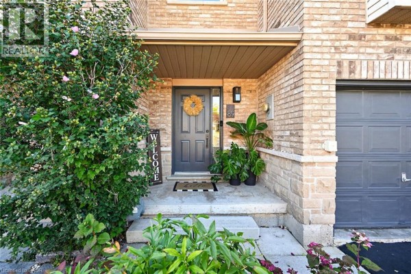Front entrance of a townhouse with a dark gray door, stone accents, and plants. - 4055 Forest Run Avenue Unit# 89, Burlington