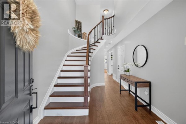 Interior view of a foyer with a curved staircase, hardwood floors, and gray walls. - 4055 Forest Run Avenue Unit# 89, Burlington