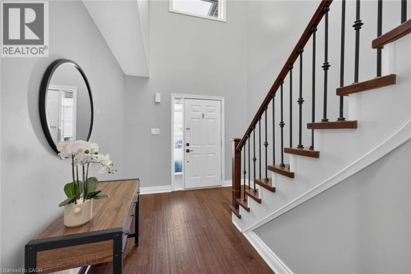 Foyer with a curved staircase, hardwood floors, gray walls, and a console table. - 4055 Forest Run Avenue Unit# 89, Burlington