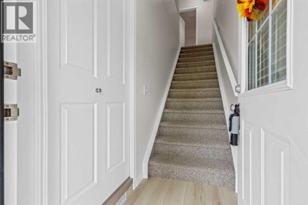 Interior view of a townhouse entrance with white doors and carpeted stairs. - 406, 140 Sagewood Boulevard Sw, Airdrie
