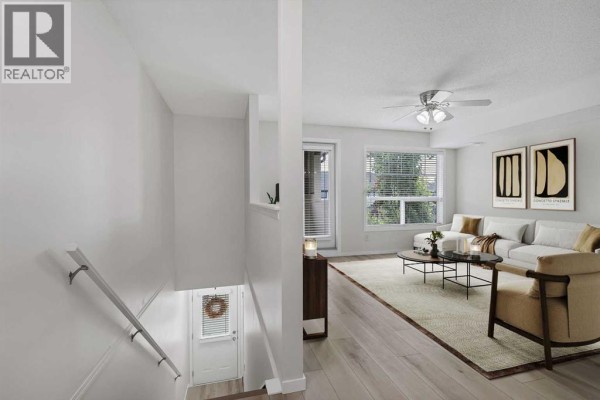 View from stairs looking down at entrance and up into a furnished living room. - 406, 140 Sagewood Boulevard Sw, Airdrie