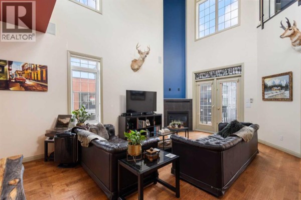 Living room with dark leather sofas, a fireplace, and a mounted deer head. - 406, 527 15 Avenue Sw, Calgary