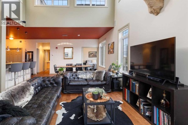 Open-concept living area with a large sectional sofa, dining area, and kitchen island. - 406, 527 15 Avenue Sw, Calgary
