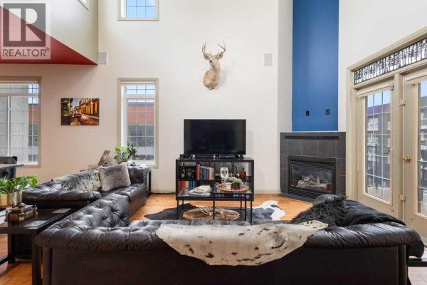 Living room with a fireplace, mounted deer head, and double glass doors. - 406, 527 15 Avenue Sw, Calgary