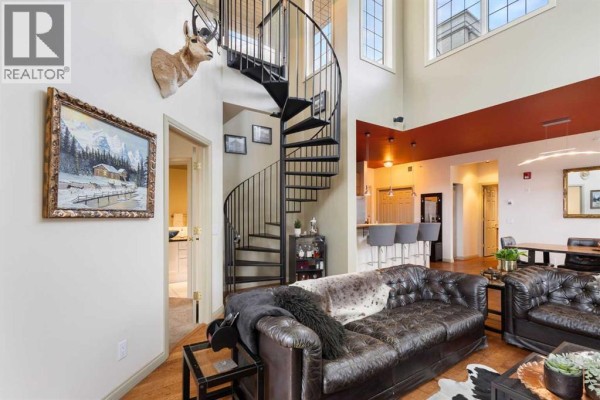 Living room featuring a spiral staircase, leather sofa, and a glimpse of the kitchen. - 406, 527 15 Avenue Sw, Calgary