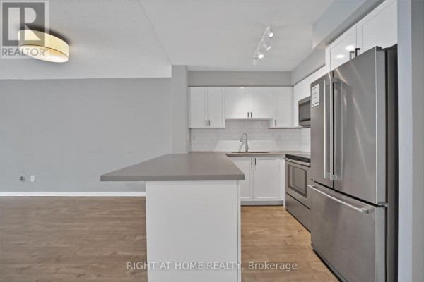 Open concept kitchen and living area with a breakfast bar and hardwood floors. - 406 - 18 Stafford Street, Toronto